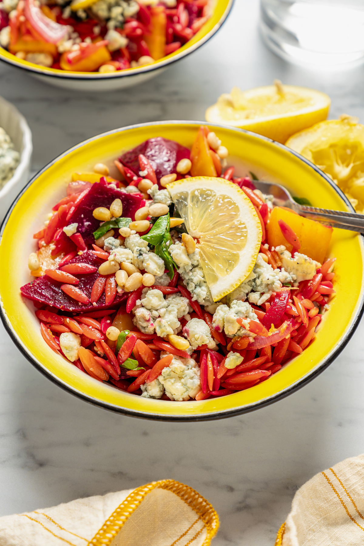 This vibrant Orzo Salad is made with beets, pasta, toasted pine nuts, and blue cheese - a wholesome side dish that everyone will love. Beet and orzo salad with pine nuts, blue cheese, and more.