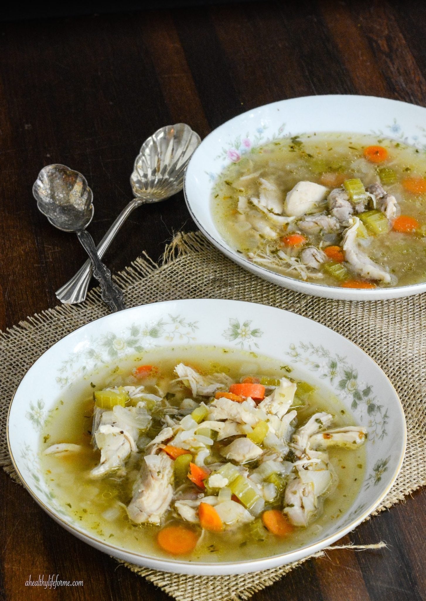 This easy paleo chicken soup recipe with fresh veggies and herbs is a comforting weeknight dinner you'll love. Two bowls of soup.