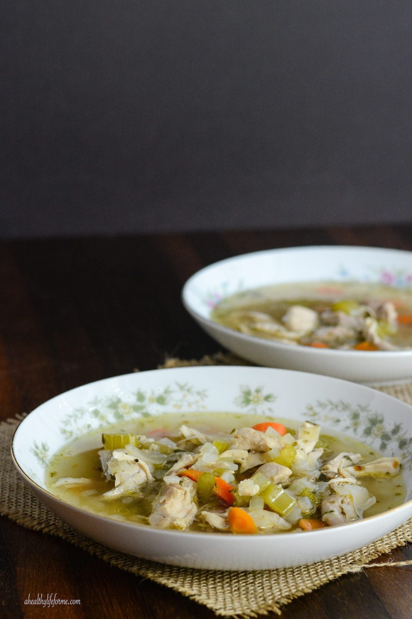 This easy paleo chicken soup recipe with fresh veggies and herbs is a comforting weeknight dinner you'll love. Side view of paleo chicken soup in a bowl.