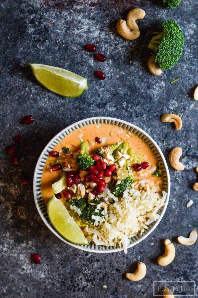 Paleo Thai Curry Chicken is a healthy, feel-good dinner recipe. Addictively delicious Thai-inspired flavors, ready in less than 30 minutes! Overhead shot of chicken curry with lime wedge, cashews, and pomegranate.