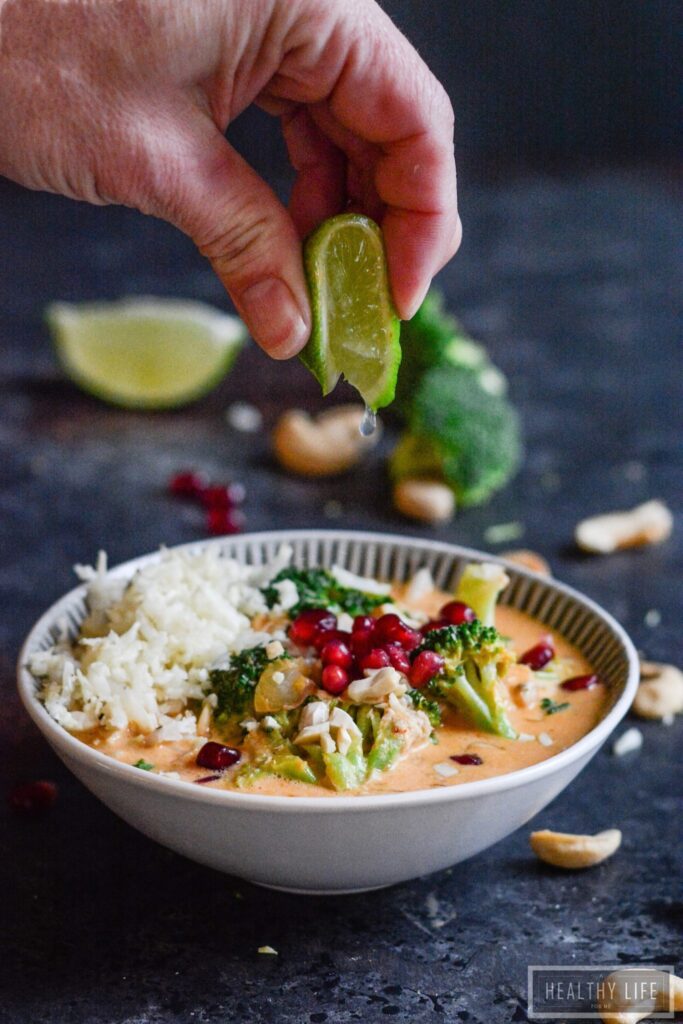 Paleo Thai Curry Chicken is a healthy, feel-good dinner recipe. Addictively delicious Thai-inspired flavors, ready in less than 30 minutes! Squeezing a lime wedge over a bowl of paleo thai curry chicken.