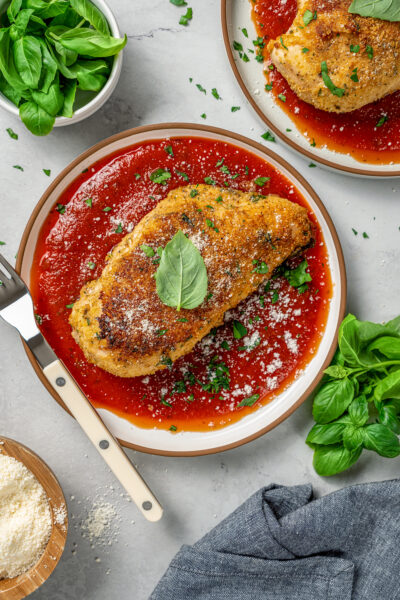Parmesan crusted chicken on a plate with marinara sauce.