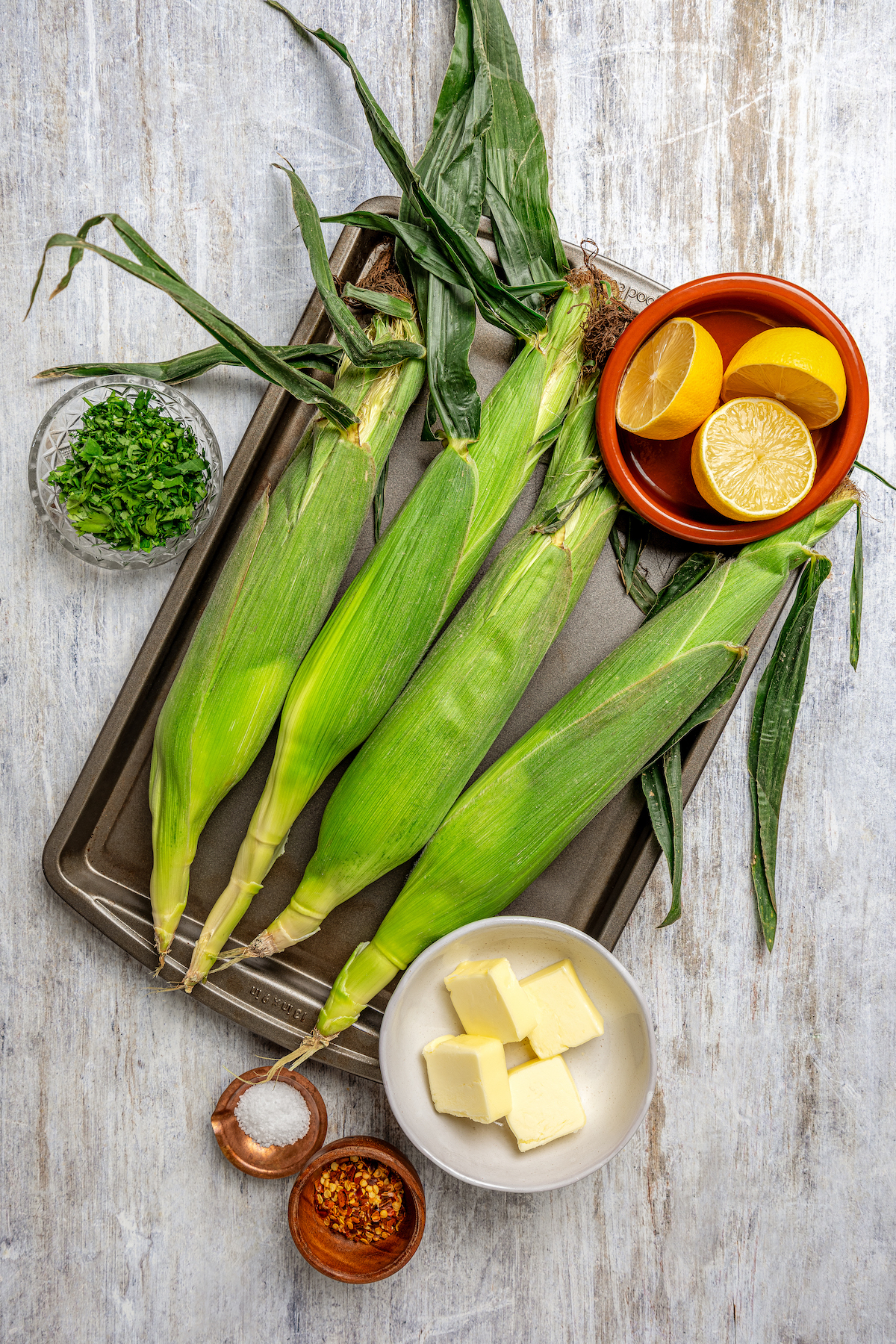 Sweet, fresh corn is a must-have in the summer, and this easy Grilled Corn is loaded with a unique nutty taste that you're sure to love! Ingredients for grilled corn arranged on a cutting board.