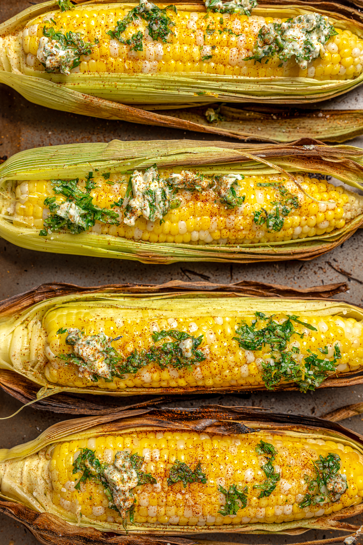 Sweet, fresh corn is a must-have in the summer, and this easy Grilled Corn is loaded with a unique nutty taste that you're sure to love! Grilled corn on a baking sheet with compound butter.