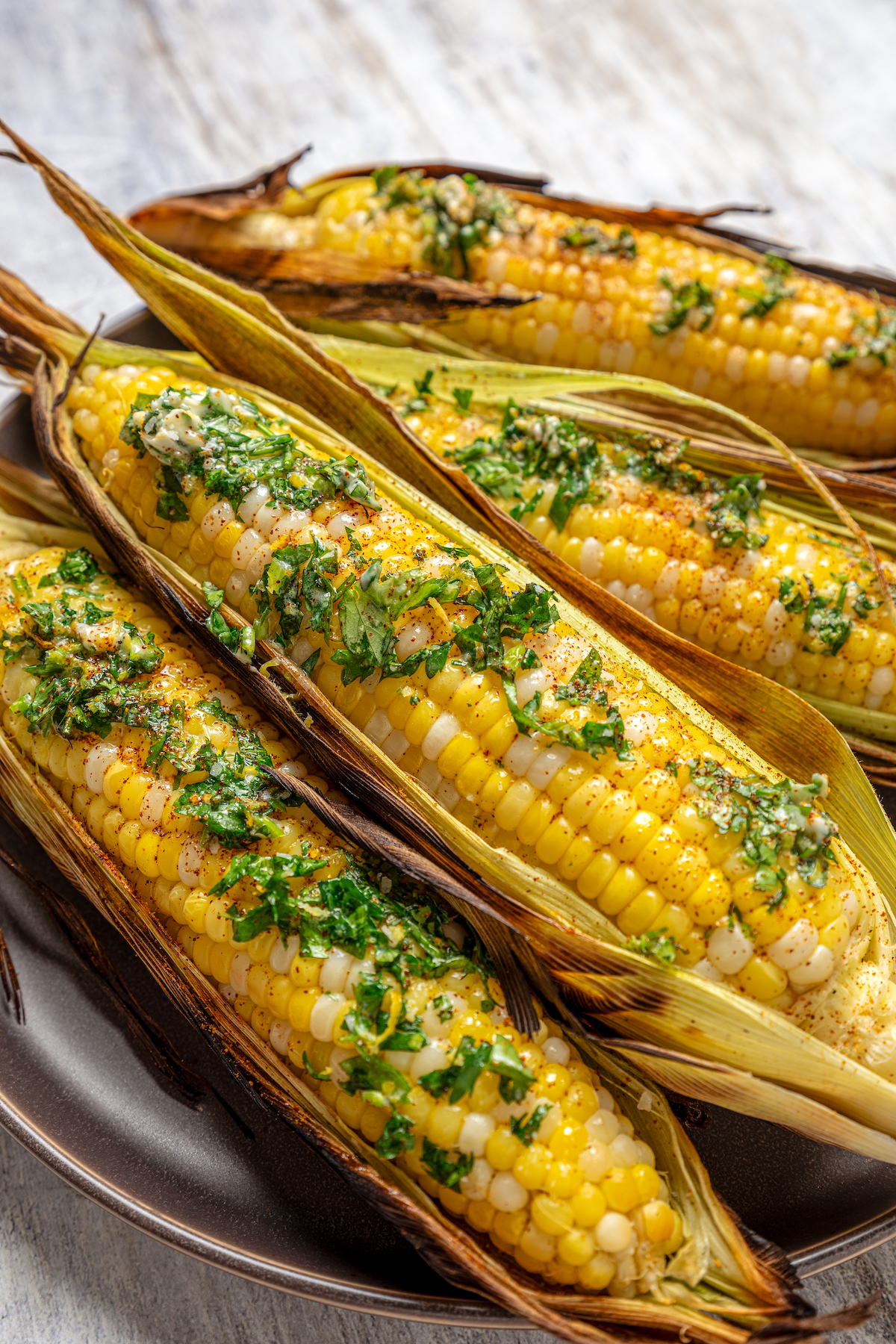 Sweet, fresh corn is a must-have in the summer, and this easy Grilled Corn is loaded with a unique nutty taste that you're sure to love! Grilled corn on a serving plate.