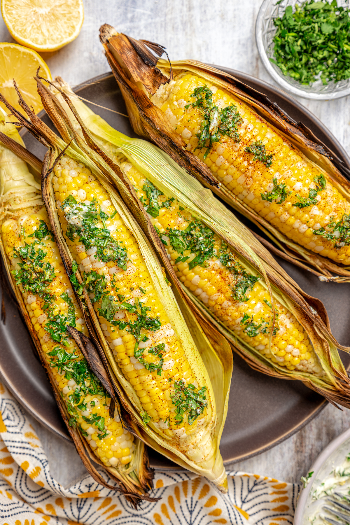 Sweet, fresh corn is a must-have in the summer, and this easy Grilled Corn is loaded with a unique nutty taste that you're sure to love! Overhead shot of grilled corn ears, topped with cilantro butter.