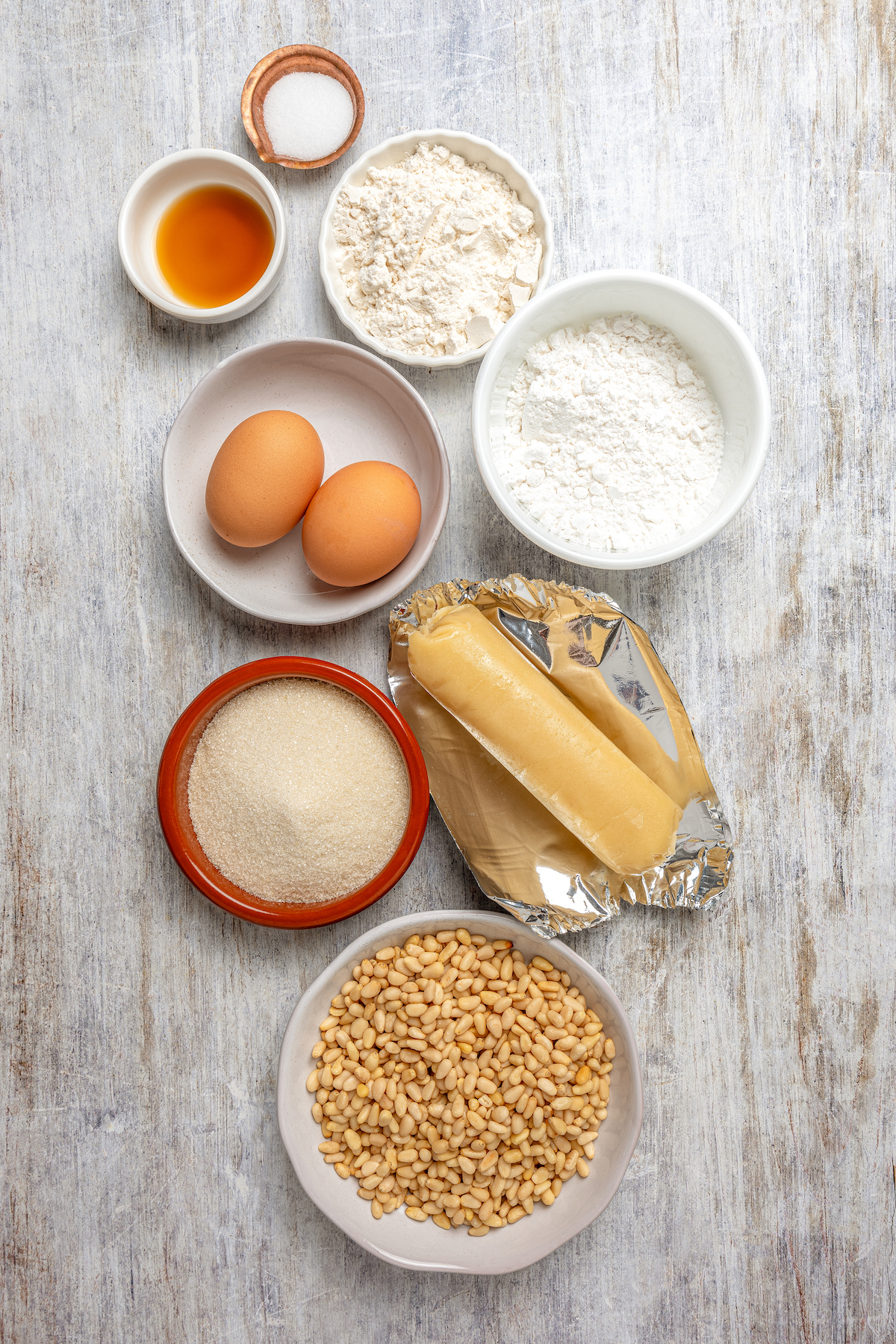 Italian Pignoli Cookies are crispy, chewy and almond-y, topped with rich, creamy pine nuts. They're sure to become a family favorite! Ingredients for pignoli cookies arranged on a work surface.