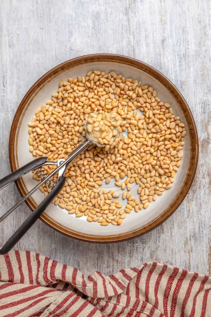 Italian Pignoli Cookies are crispy, chewy and almond-y, topped with rich, creamy pine nuts. They're sure to become a family favorite! Dipping the cookie dough in pine nuts.