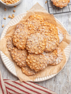 A plate of pignoli cookies, dusted with powdered sugar.