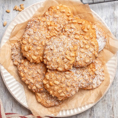A plate of pignoli cookies, dusted with powdered sugar.