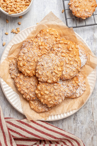 A plate of pignoli cookies, dusted with powdered sugar.