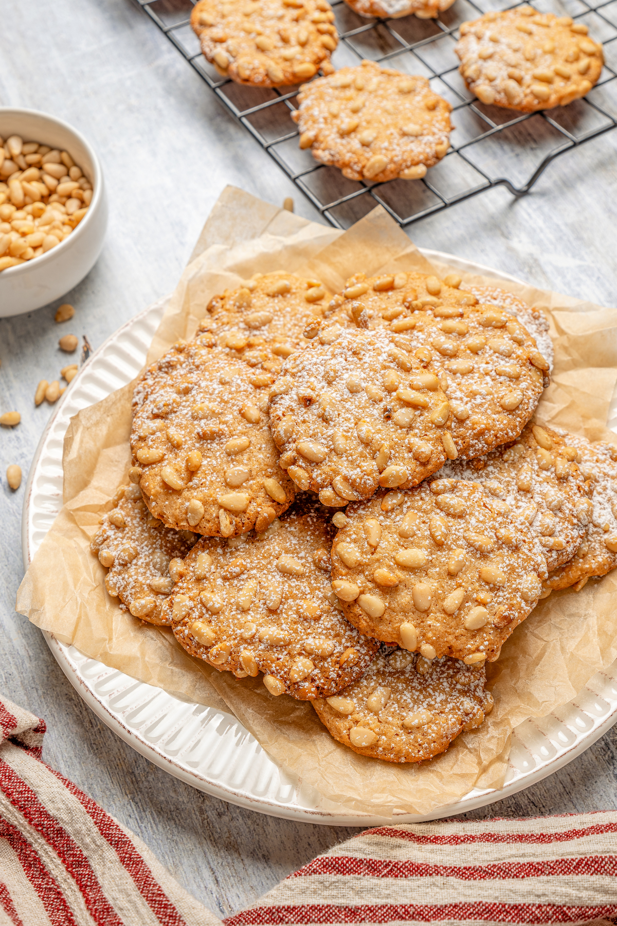 Italian Pignoli Cookies are crispy, chewy and almond-y, topped with rich, creamy pine nuts. They're sure to become a family favorite! Homemade Italian Christmas cookies on a plate.