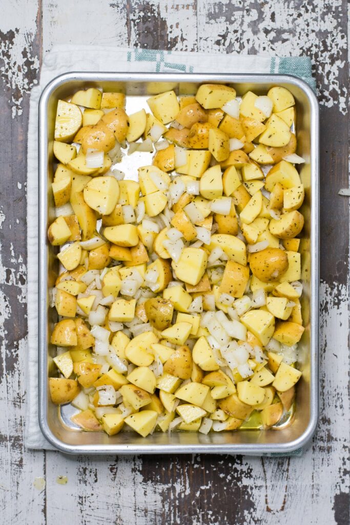 Seasoned potatoes, tender onions, and hearty sausage make this recipe for Baked Breakfast Potatoes with Sausage is a true crowd-pleaser. Seasoned onions and potatoes on a sheet pan.