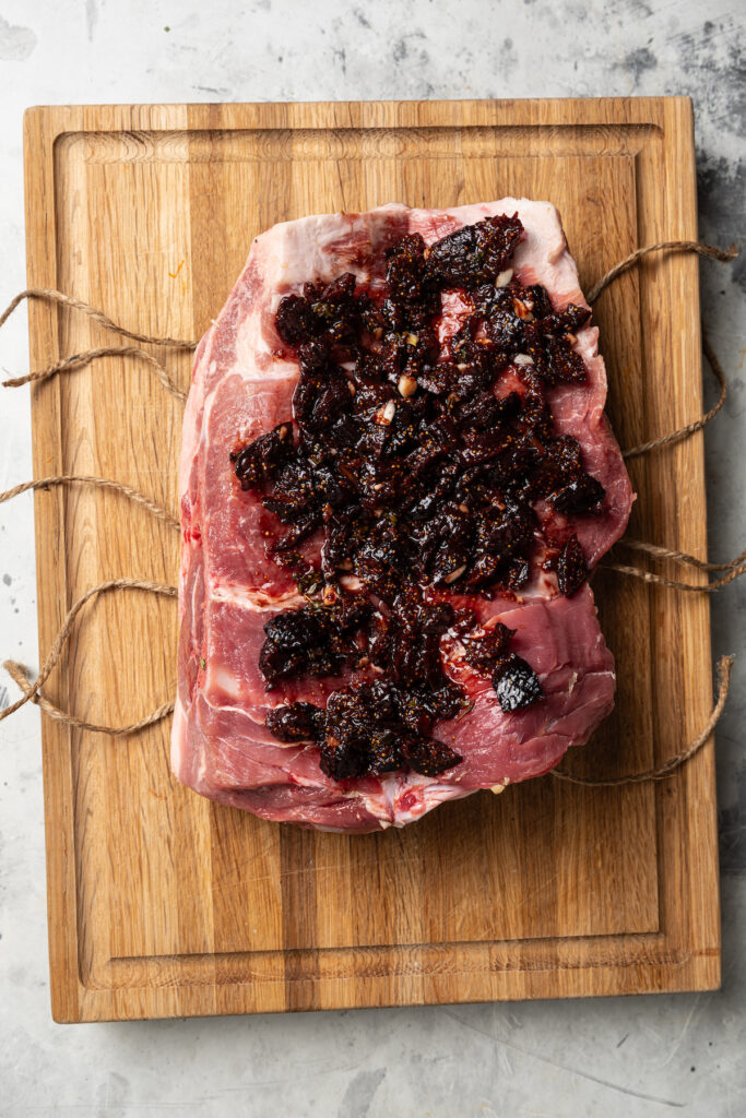 This sweet-and-savory pork shoulder recipe with honey, red wine-fig sauce, and lots of fruity figs is perfect for Thanksgiving dinners. Spreading the garlic-fig mixture on the pork.
