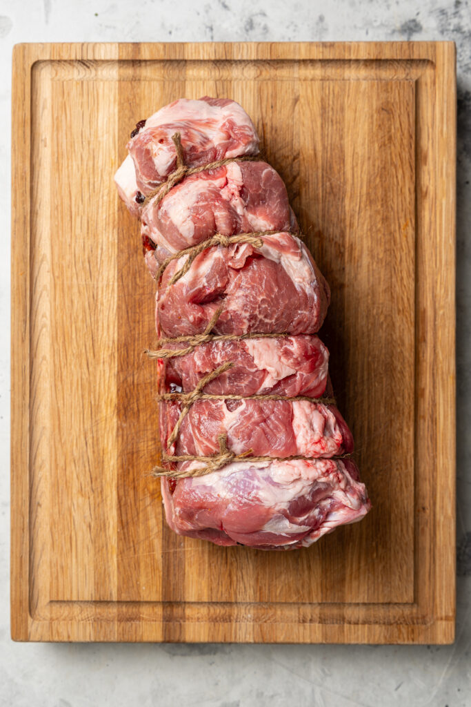 This sweet-and-savory pork shoulder recipe with honey, red wine-fig sauce, and lots of fruity figs is perfect for Thanksgiving dinners. Tied-up pork shoulder with the filling inside.