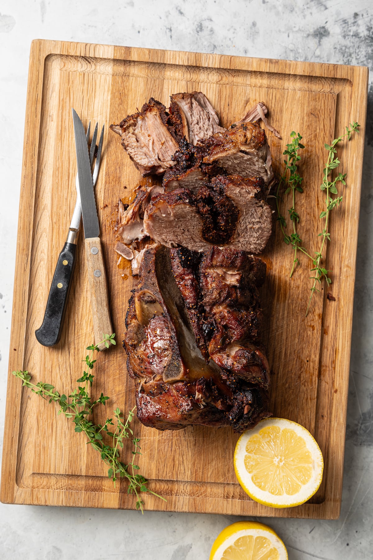 This sweet-and-savory pork shoulder recipe with honey, red wine-fig sauce, and lots of fruity figs is perfect for Thanksgiving dinners. Slicing into the juicy, roasted pork shoulder on a cutting board.