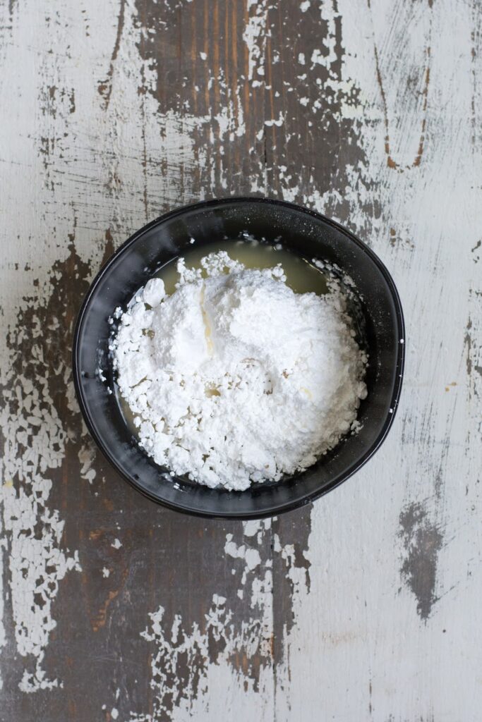 These are the perfect Gluten Free Lemon Poppyseed Muffins. Real lemon and crunchy poppy seeds in a tender, sweet muffin. Easy to make! Powdered sugar and lemon juice in a small earthenware bowl.