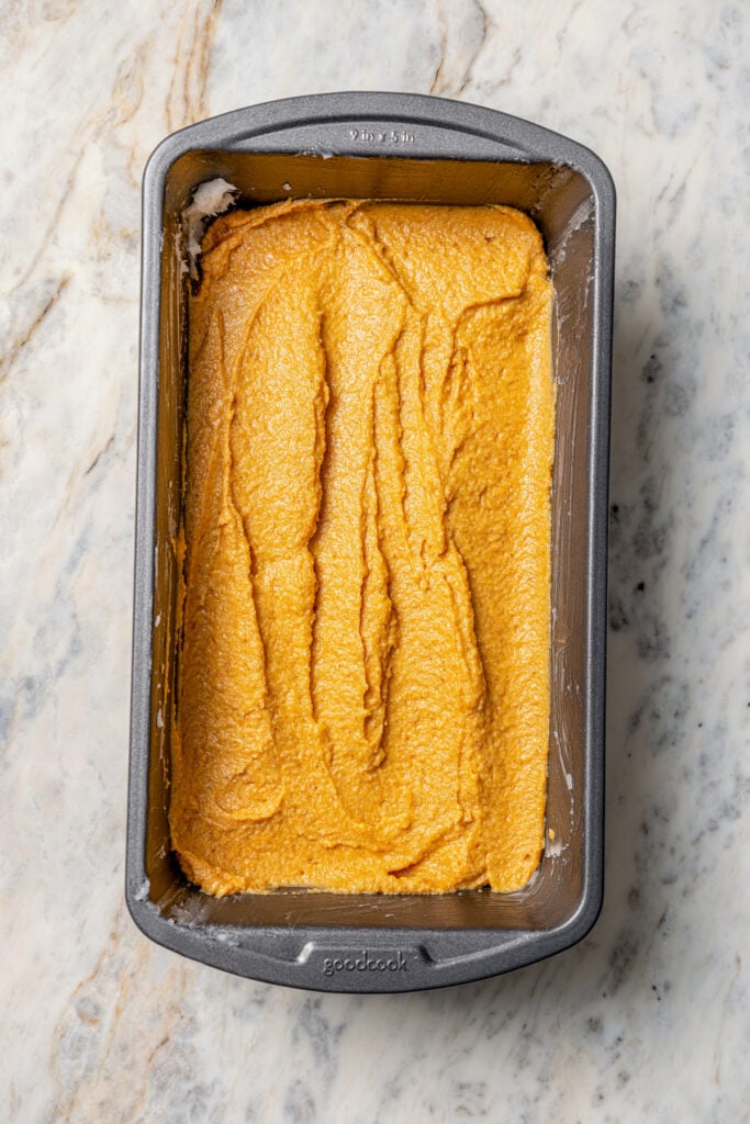 This tender paleo pumpkin bread recipe with vegan flours, coconut cream, and maple syrup is an easy fall-flavored dessert. Pouring the batter into the loaf pan.