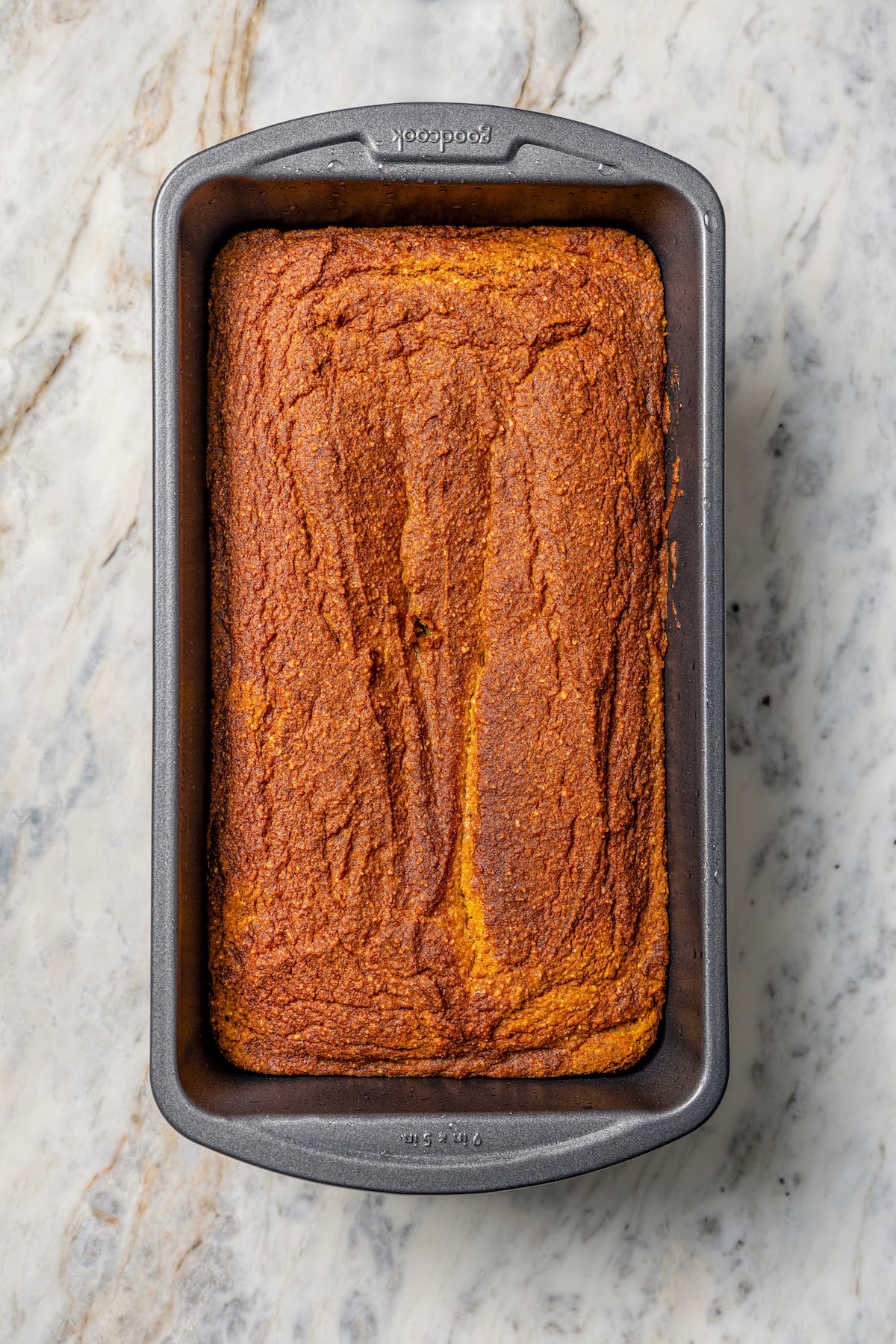 This tender paleo pumpkin bread recipe with vegan flours, coconut cream, and maple syrup is an easy fall-flavored dessert. Baked loaf in the pan.