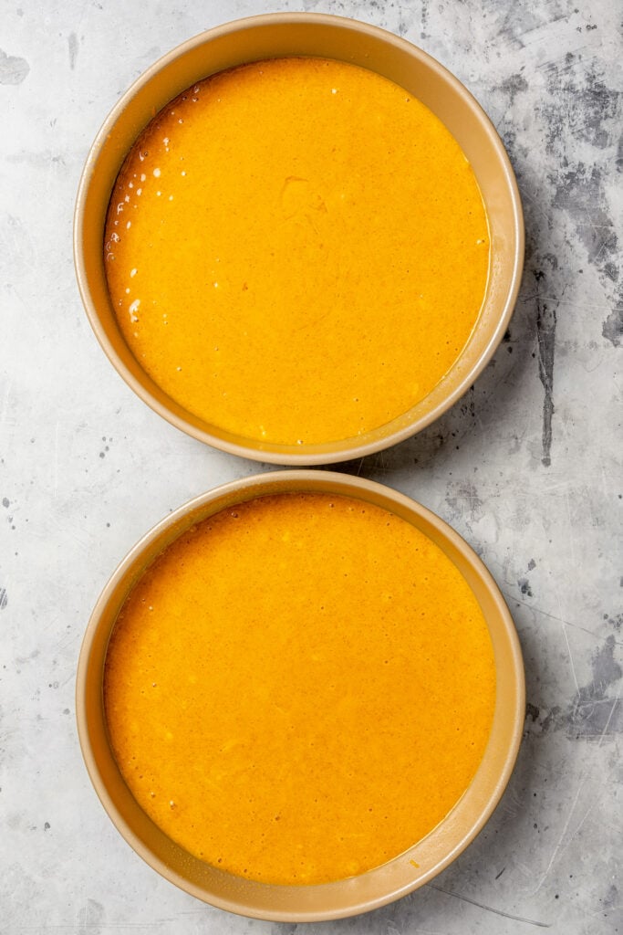 This warmly spiced pumpkin cake recipe with velvety cream cheese-chocolate frosting is a sweet end to any Thanksgiving dinner. Divided cake batter in the cake pans.