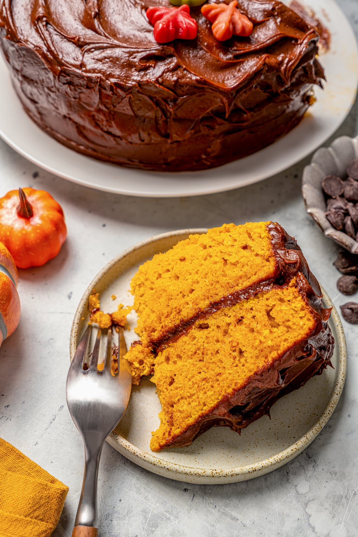 This warmly spiced pumpkin cake recipe with velvety cream cheese-chocolate frosting is a sweet end to any Thanksgiving dinner. Digging into a slice of cake with fluffy chocolate frosting.