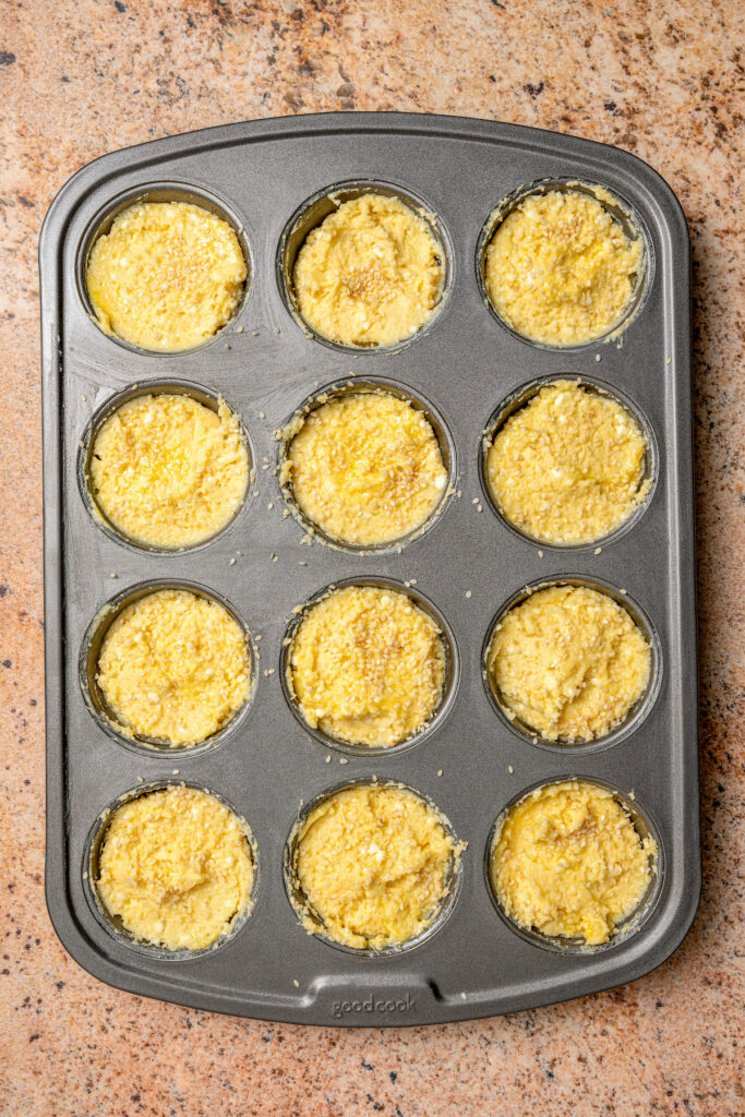 This buttery breakfast muffins recipe is packed with creamy cottage cheese and parmesan for a tender bite. Pouring batter into the muffin tray.