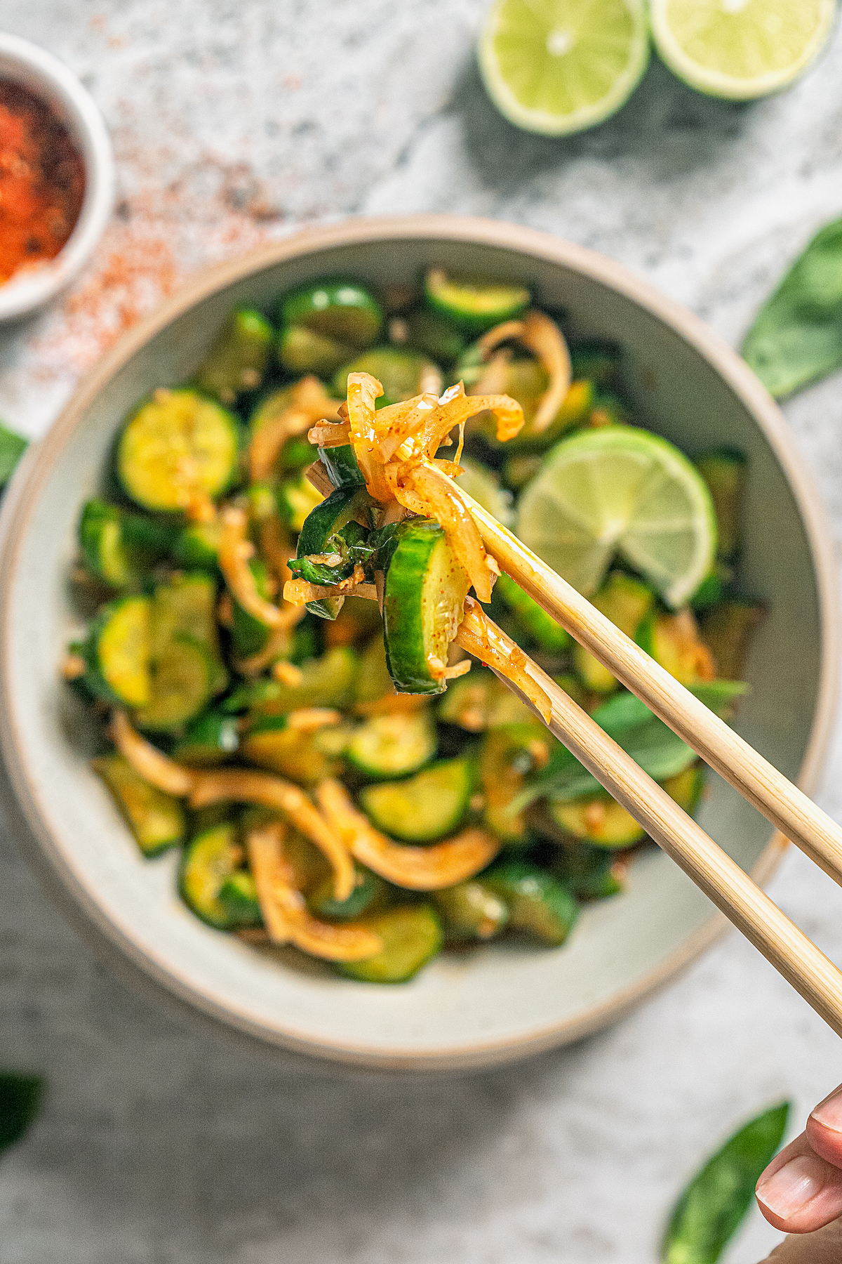 This easy cucumber kimchi recipe with gochugaru pepper and tangy fish sauce is the fastest way to put Korean kimchi on the table for dinner. Close-up of a bit of kimchi in between chopsticks.
