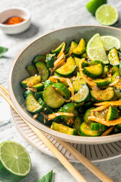 Cucumber kimchi in a bowl with chopsticks on the side.