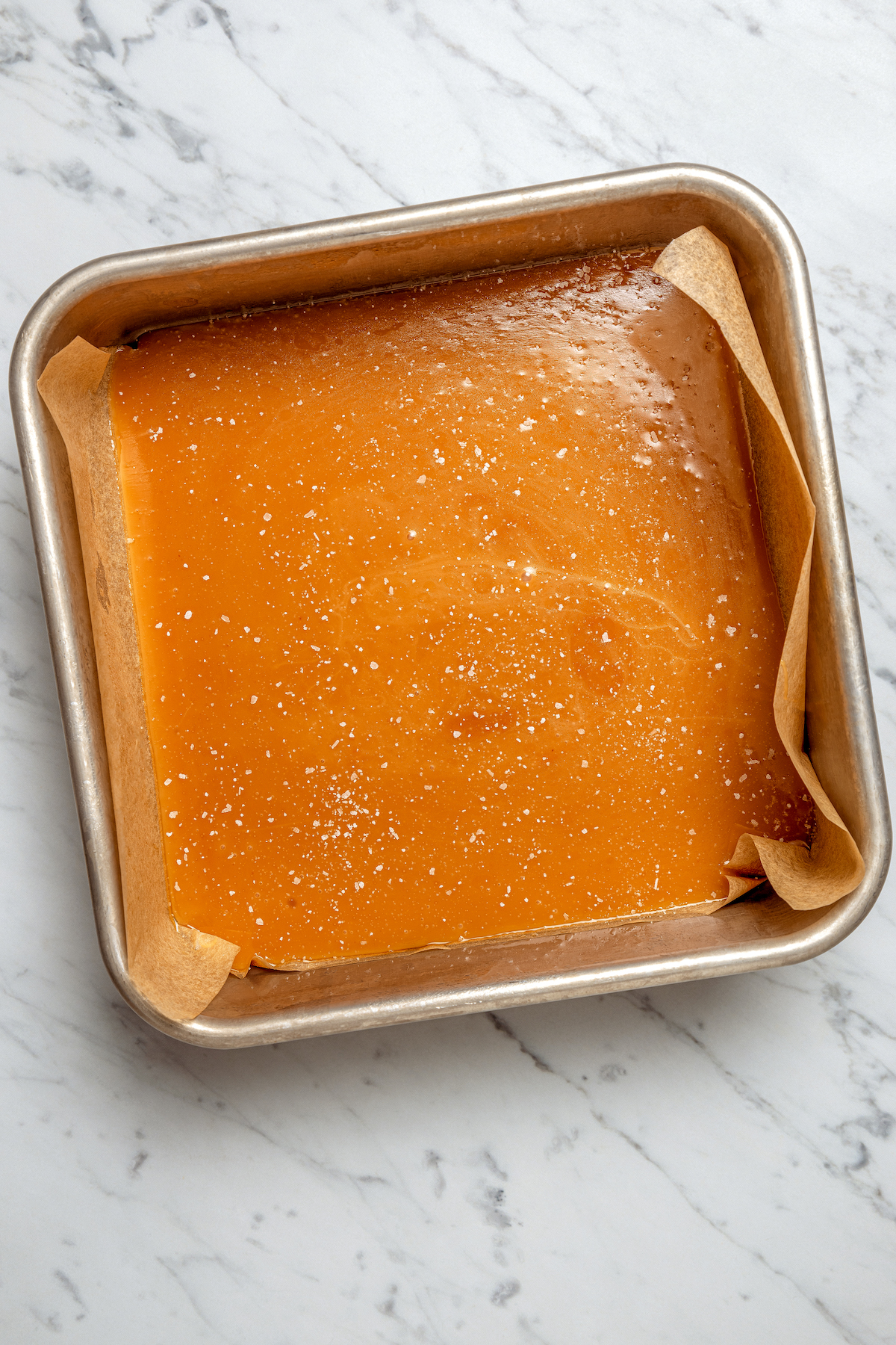 These Whiskey Salted Caramels are the perfect Fall candy recipe - who could resist silky caramel, warm whiskey, and a touch of salt? Cooled whiskey caramel mixture in a square pan.