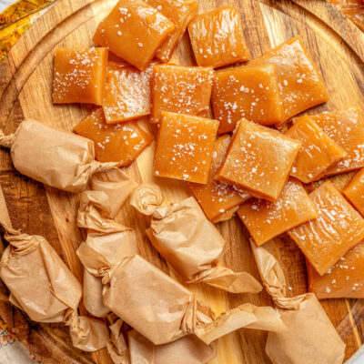 A cutting board with salted caramels, some wrapped in homemade wrappers.