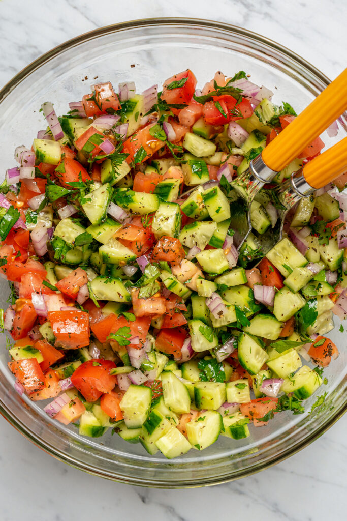 This quick shirazi salad with cucumbers, tomatoes, red onions, and a light vinaigrette is a refreshing Middle Eastern side you'll love. Mixed salad in a bowl.