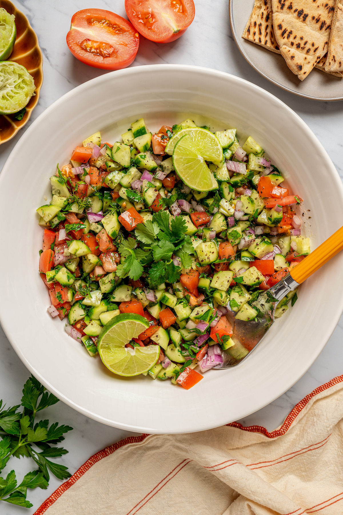 This quick shirazi salad with cucumbers, tomatoes, red onions, and a light vinaigrette is a refreshing Middle Eastern side you'll love. Bowl of fresh Persian salad with fresh herbs and lime wedges.