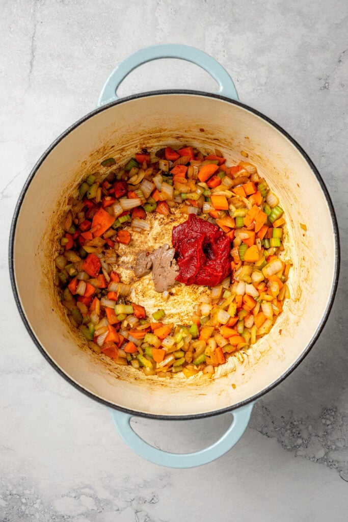 This garlicky slow cooker short ribs recipe with red wine, tender veggies, and dried herbs is an easy but fancy dinner. Adding the tomato paste and anchovy paste to the center of the Dutch oven.