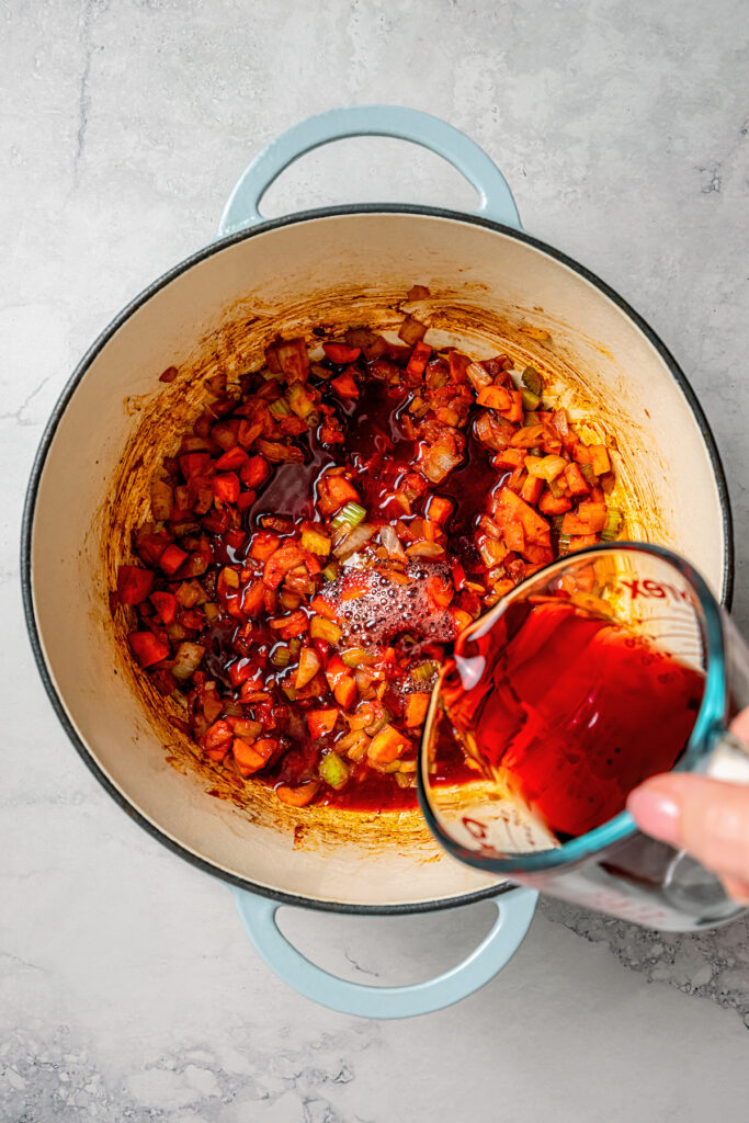 This garlicky slow cooker short ribs recipe with red wine, tender veggies, and dried herbs is an easy but fancy dinner. Pouring in the wine to deglaze the Dutch oven.