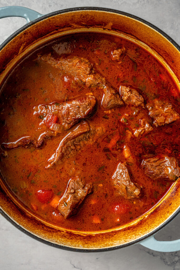 This garlicky slow cooker short ribs recipe with red wine, tender veggies, and dried herbs is an easy but fancy dinner. Cooked short ribs in the Dutch oven.