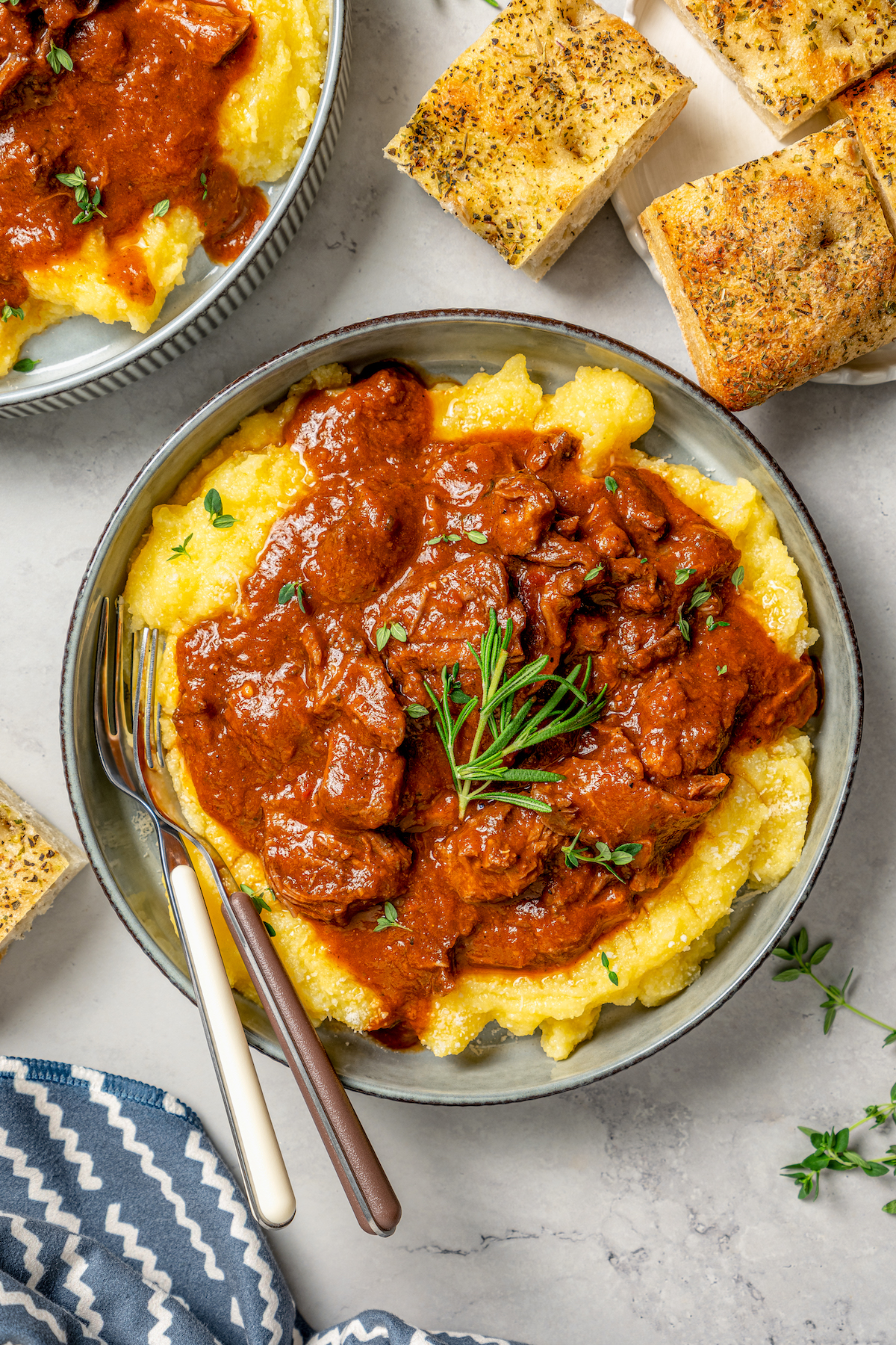 This garlicky slow cooker short ribs recipe with red wine, tender veggies, and dried herbs is an easy but fancy dinner. Large bowl of slow cooker short ribs served over parmesan polenta.