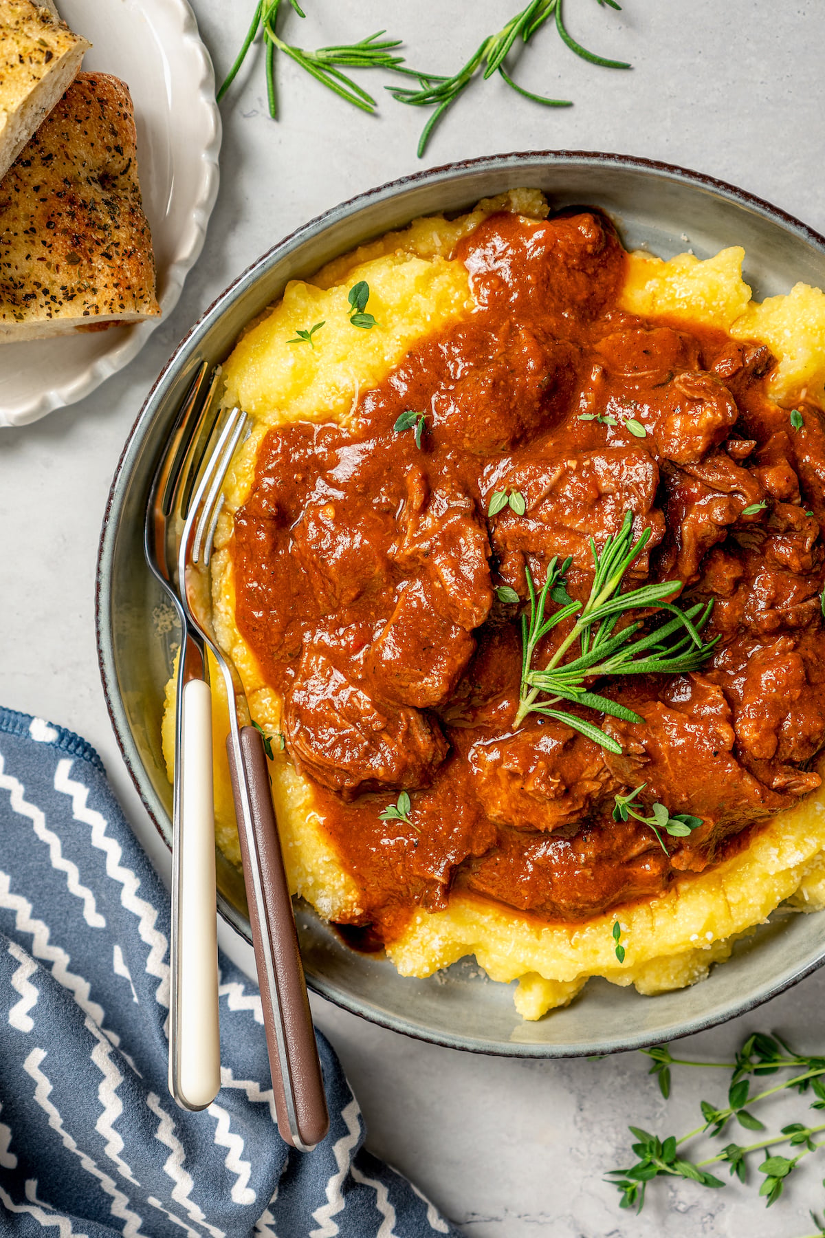 This garlicky slow cooker short ribs recipe with red wine, tender veggies, and dried herbs is an easy but fancy dinner. Tomatoey short ribs with fresh rosemary served over polenta.