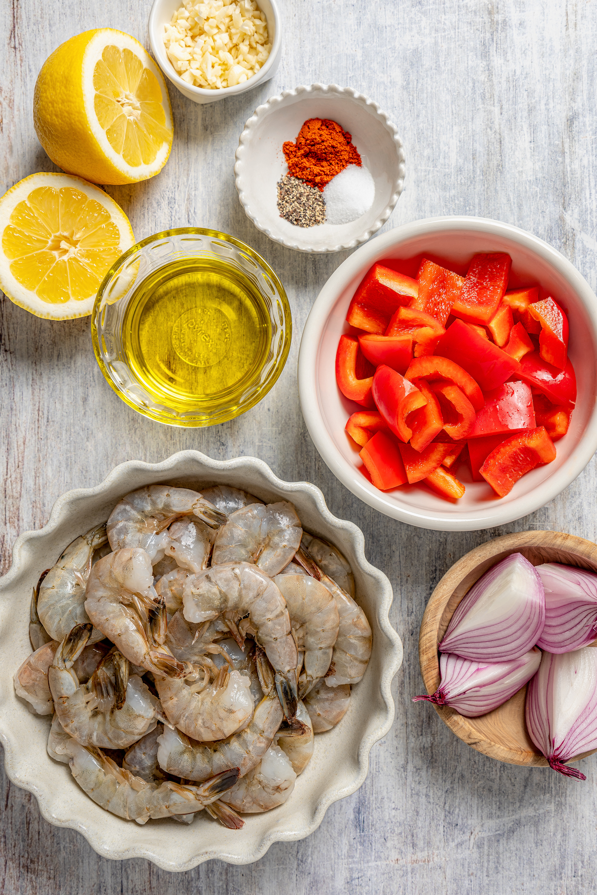 This shrimp brochette recipe with garlic-lemon marinade, sweet bell peppers, and spicy red onions is an easy 20-minute lunch. Ingredients for making a shrimp brochette.