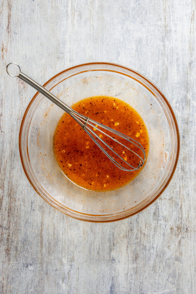 This shrimp brochette recipe with garlic-lemon marinade, sweet bell peppers, and spicy red onions is an easy 20-minute lunch. Whisked marinade in a bowl.