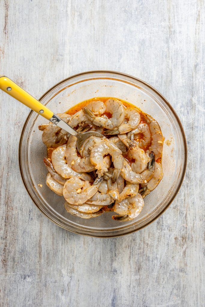 This shrimp brochette recipe with garlic-lemon marinade, sweet bell peppers, and spicy red onions is an easy 20-minute lunch. Mixing the shrimp with the marinade.