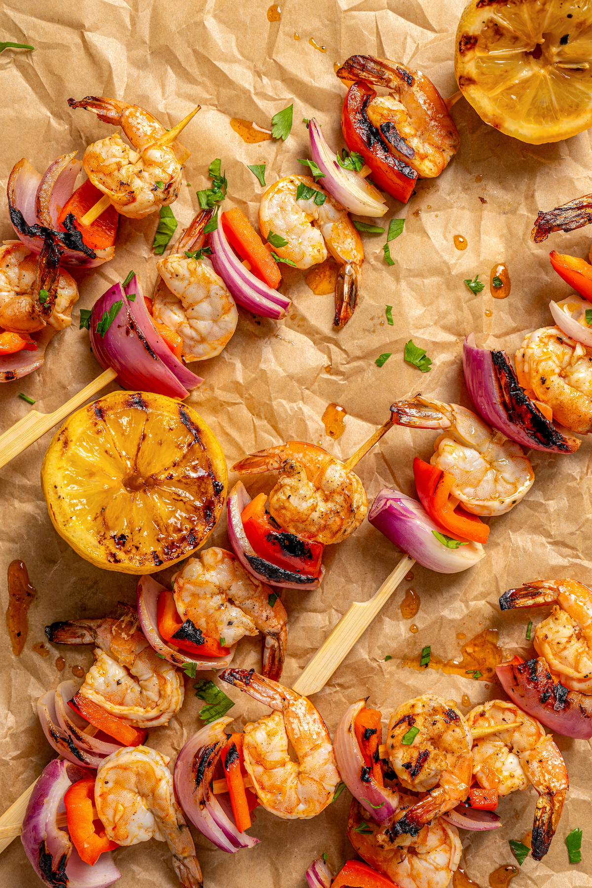 This shrimp brochette recipe with garlic-lemon marinade, sweet bell peppers, and spicy red onions is an easy 20-minute lunch. Grilled brochettes with shrimp and veggies on a piece of parchment.