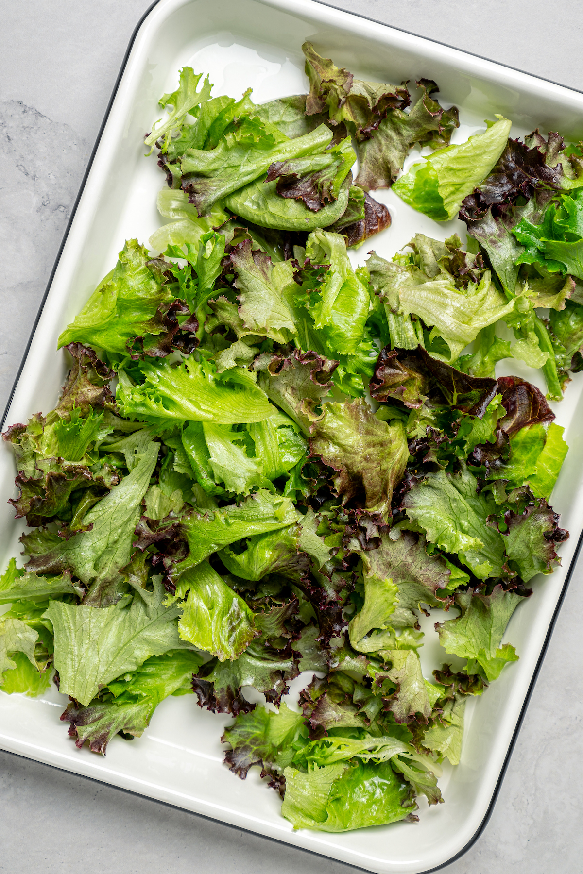 Spring Mix Salad with Champagne Dressing is elegant, flavorful, and unique - and only takes minutes to prepare! A nutritious, paleo salad. Spring mix on an enamel tray.
