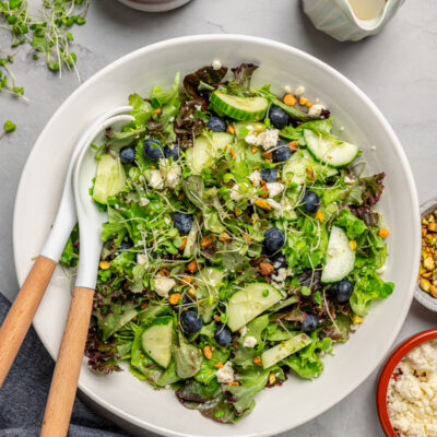 A salad bowl with salad and matching utensils.