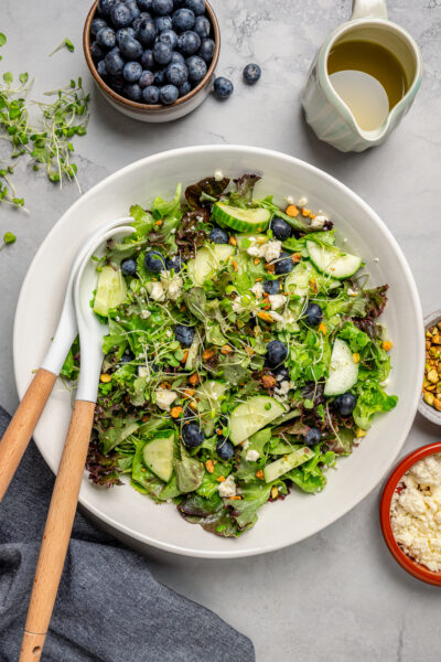 A salad bowl with salad and matching utensils.