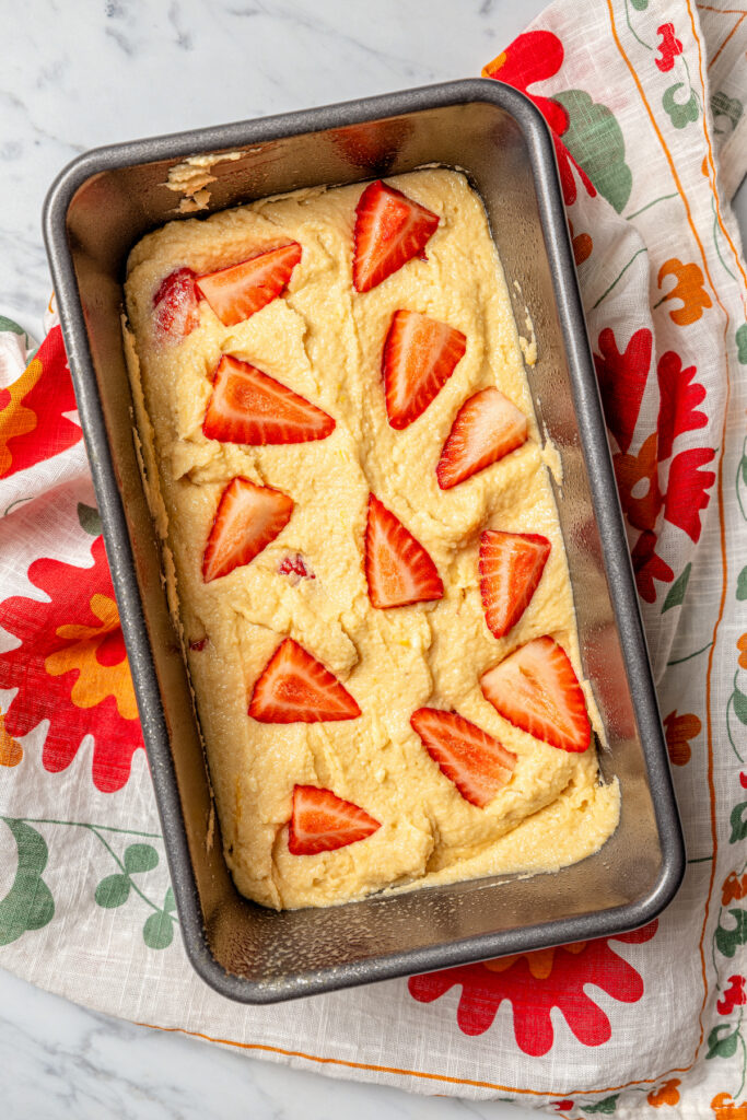 This fluffy, sour cream-strawberry bread recipe with sweet maple syrup is an easy breakfast option with your favorite coffee. Spreading the batter in the greased loaf pan.