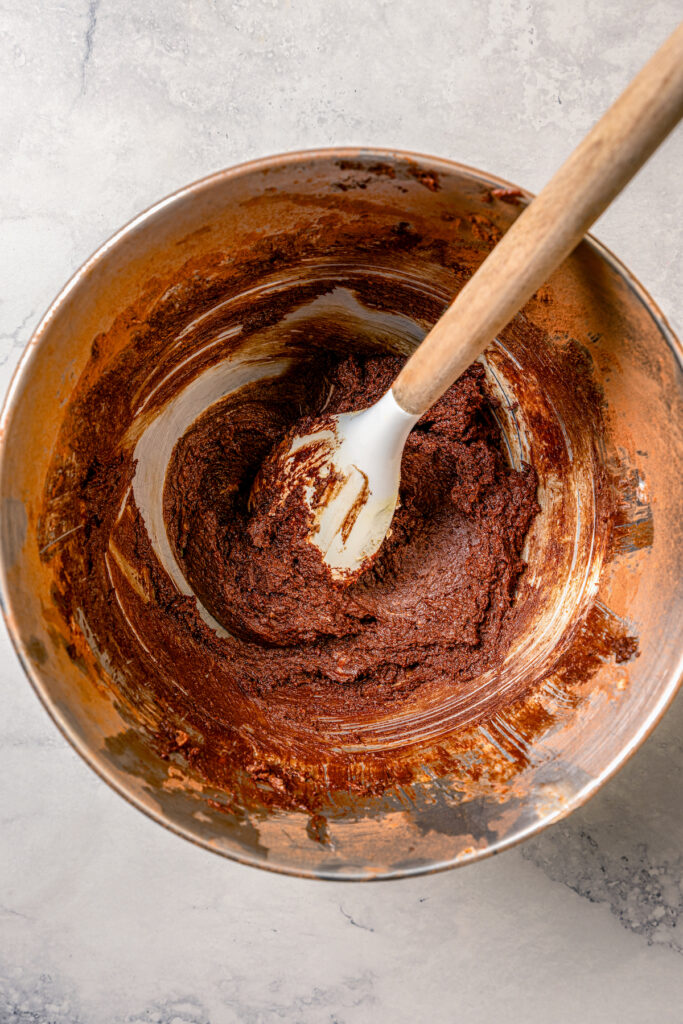 This fluffy strawberry cake recipe with homemade chocolate-maple frosting is an easy but impressive Valentine's Day dessert. Mixing the chocolate frosting in a bowl.