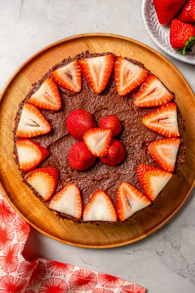 This fluffy strawberry cake recipe with homemade chocolate-maple frosting is an easy but impressive Valentine's Day dessert. Chocolate-frosted cake decorated with sliced strawberries.
