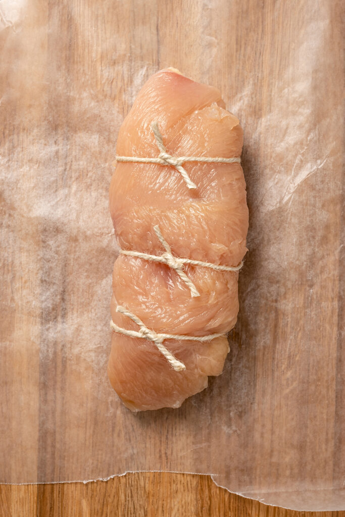 Stuffed Chicken Breasts pack so much flavor in every bite! With goat cheese, basil and white wine mushroom sauce, it's fancy but easy to make. Rolled-up chicken breast tied with kitchen twine.