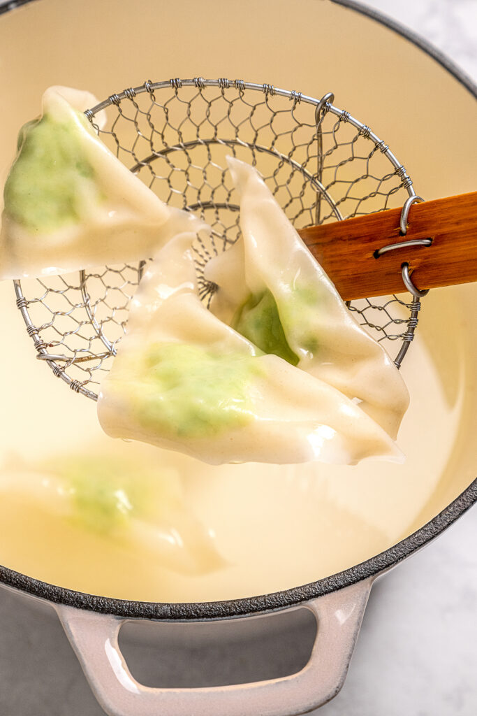 Cheese Ravioli with Peas and Butter Sauce will soon become one of your family's favorites. Easy to make with wonton wrappers! Lowering ravioli into a pot of boiling water.