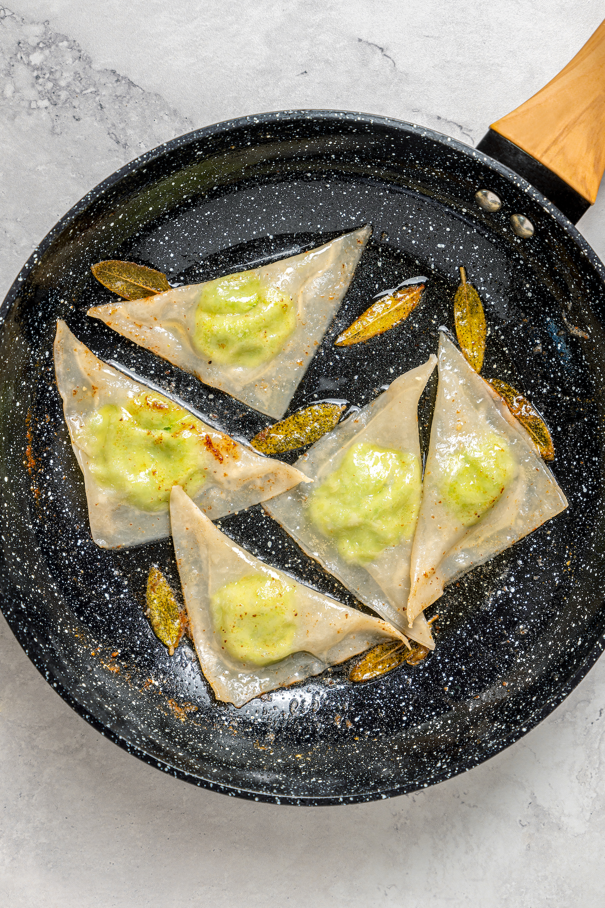 Cheese Ravioli with Peas and Butter Sauce will soon become one of your family's favorites. Easy to make with wonton wrappers! Adding cooked ravioli to butter sauce in a skillet.